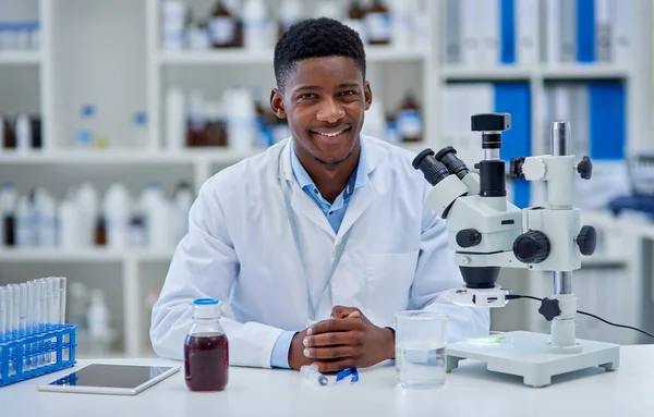 Es war ein langer produktiver Tag. Porträt eines fröhlichen jungen Wissenschaftlers, der tagsüber an seinem Schreibtisch in einem Labor steht. — Stockfoto