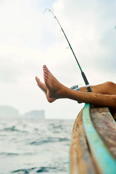 Dőlj hátra és várd, hogy harapjanak. Vágott kép egy felismerhetetlen fiatalemberről, aki a tengeren horgászik a hajóján.. — Stock Fotó