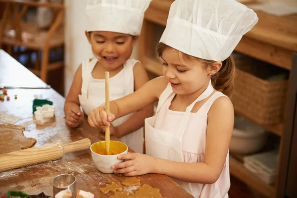 Memanggang sangat menyenangkan. Dua gadis kecil bersenang-senang saat memanggang di dapur. — Stok Foto