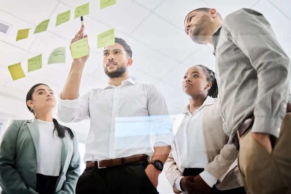 Establecer la estrategia correcta. Fotografía de bajo ángulo de un grupo de empresarios haciendo una lluvia de ideas juntos en una pantalla de vidrio en una oficina. — Foto de Stock