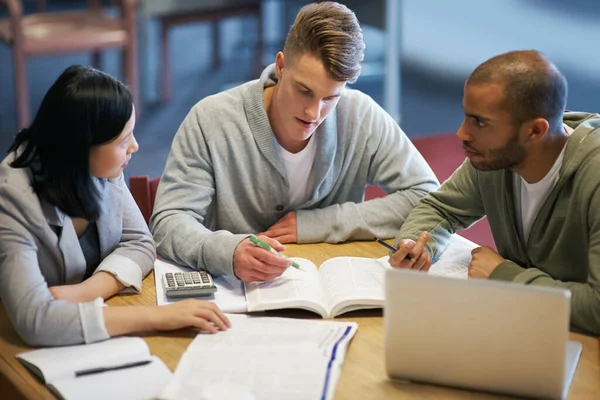 Cramming algum conhecimento de última hora. Um grupo de jovens que estudam juntos na biblioteca. — Fotografia de Stock