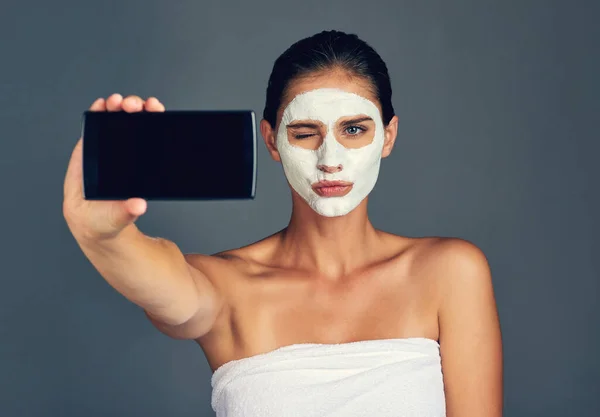 Lidem na mém blogu se to bude líbit. Studio sho mladé ženy s selfie při nošení masky obličeje. — Stock fotografie