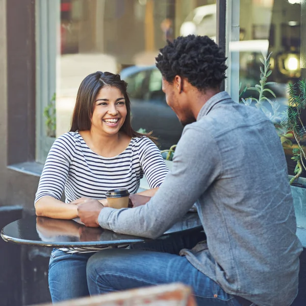 Estão a dar-se bem no primeiro encontro com um café. Tiro de um jovem casal em uma data de café em um café na calçada. — Fotografia de Stock