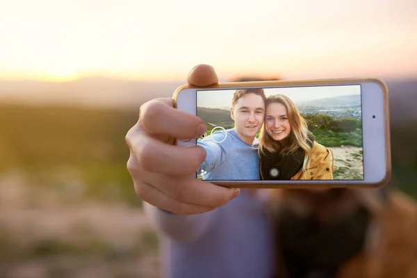 Estão sempre prontos para selfie. Tiro de um jovem casal feliz tirando uma selfie ao ar livre. — Fotografia de Stock