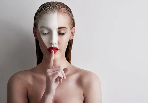 La belleza es arte. Foto de una hermosa mujer con pintura facial y lápiz labial rojo sobre un fondo liso. —  Fotos de Stock