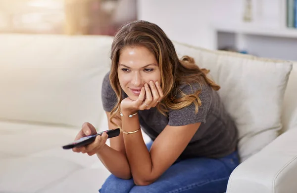 Turn off the outside world, turn on the tv. Shot of a young woman spending a relaxing weekend at home watching tv. — Stock Photo, Image