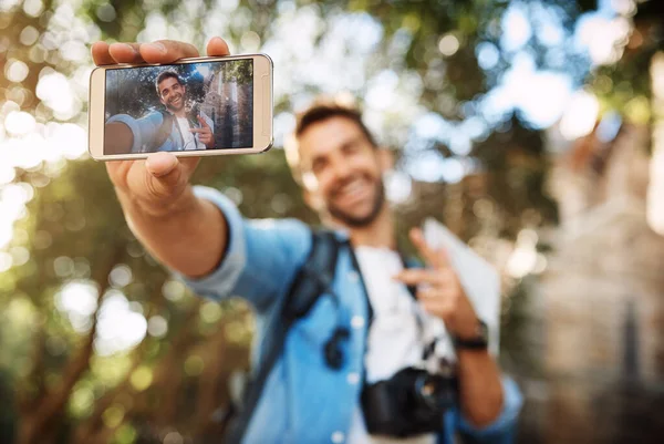 A certificar-se de que está nas fotos. Tiro cortado de um jovem bonito tirando selfies em seu telefone celular durante as férias. — Fotografia de Stock