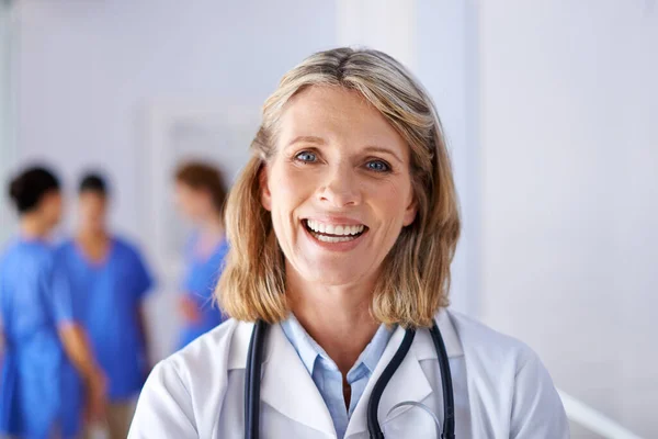 의학은 그녀의 열정이야. 뒤에서 서 있는 일단의 간호사들 과 함께 있는 성숙 한 여성 의사의 모습. — 스톡 사진