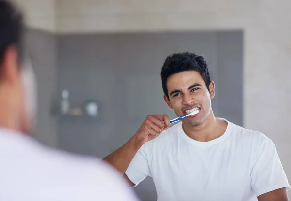 Für eine optimale Mundgesundheit bürstet er zweimal täglich. Schuss eines jungen Mannes beim Zähneputzen zu Hause. — Stockfoto
