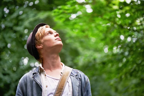 Uppskattar naturen. En ung man tar i sin omgivning när han vandrar i en skog. — Stockfoto