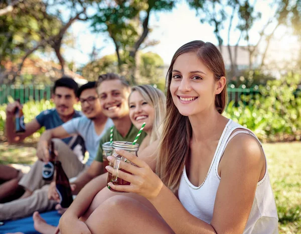 최고의 시간을 보내고 있어. 여름철해 가 뜰 때 밖에서 친구들 과 술을 마시고 있는 매력적 인 한 젊은 여자의 사진이 찍혀 있다. — 스톡 사진