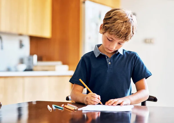 Tijd voor huiswerk, dan tijd om te spelen. Schot van een jonge jongen die zijn huiswerk doet. — Stockfoto