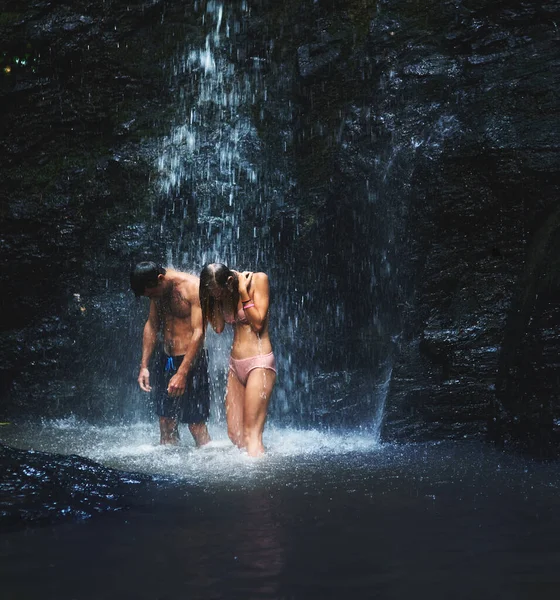 Vamos ficar assim o dia todo. Tiro de dois jovens de pé sob uma cachoeira e aproveitando cada momento dele enquanto olha para baixo. — Fotografia de Stock