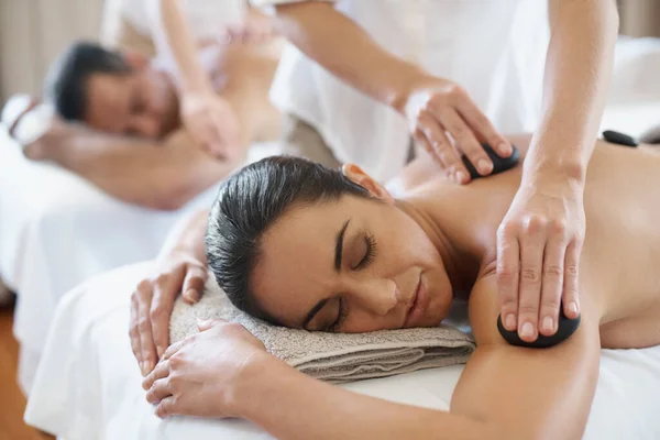 Warme stenen therapie voor diepere spierontspanning. Shot van een volwassen paar genieten van een hot stone behandeling. — Stockfoto