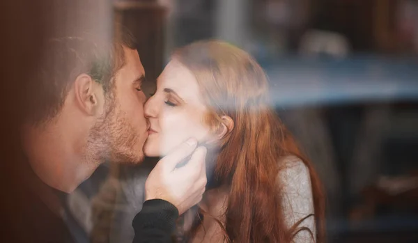 Amor en una cafetería. Una joven pareja compartiendo un beso en una cita. —  Fotos de Stock