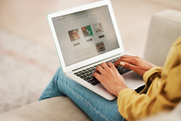 Trabajar desde casa es muy conveniente. Recortado disparo de una irreconocible mujer de negocios sentada en su sofá y blogueando desde su computadora portátil mientras estaba en casa. — Foto de Stock