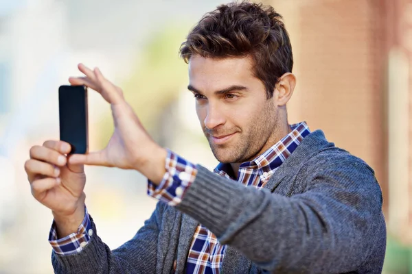 Fotografia telefónica. Tiro de um jovem bonito tirando uma foto com seu telefone celular ao ar livre. — Fotografia de Stock