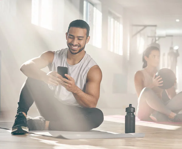 Este aplicativo me ajuda a ficar no caminho certo com meus objetivos de fitness. Tiro de um homem usando seu celular em uma pausa no ginásio. — Fotografia de Stock