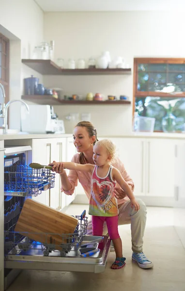 Sara 'anche piccola, ma e' di grande aiuto. Girato di una madre e una figlia utilizzando una lavastoviglie. — Foto Stock