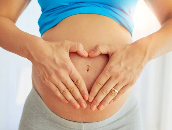 Bump amor. Foto recortada de una mujer embarazada haciendo un gesto de corazón con sus manos alrededor de su vientre. — Foto de Stock