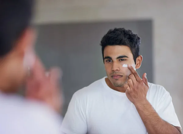 El mejor producto para el cuidado de la piel para una hidratación máxima. Foto de un joven guapo aplicándose crema hidratante en la cara. — Foto de Stock