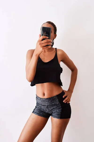 Měl bys být pyšný na tělo, pro které jsi pracoval. Studio záběr mladé ženy brát selfie při nošení její tělocvičny oblečení. — Stock fotografie