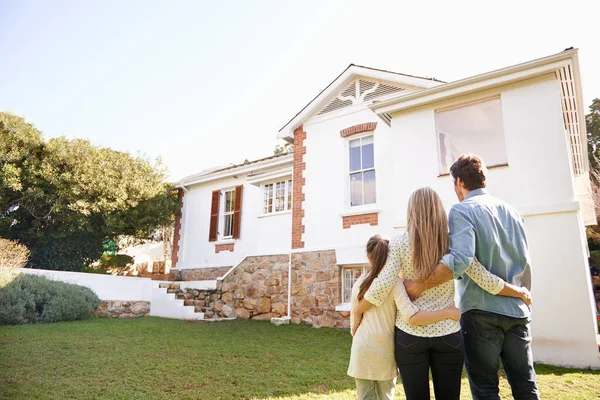 Willkommen zu Hause. Eine Familie steht draußen und bewundert ihr neues Zuhause. — Stockfoto
