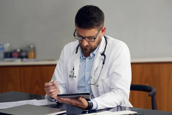 Сучасний лікар. Обрізаний знімок красивого лікаря-чоловіка, який працює на планшеті, сидячи в офісі . — стокове фото
