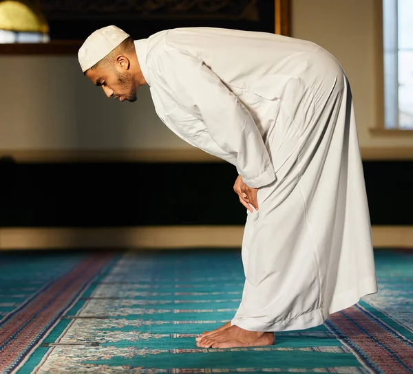 Is bidden uw stuurwiel of uw reserveband. Schot van een jonge moslim man biddend in een moskee. — Stockfoto