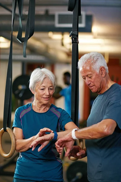 Comparando sus tiempos. Recorte de una pareja de ancianos haciendo ejercicio en el gimnasio. — Foto de Stock
