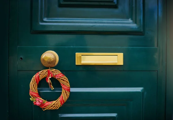 Τοκ τοκ. Κλείσιμο πράσινης πόρτας με χριστουγεννιάτικη διακόσμηση κρεμασμένη στο χερούλι έξω κατά τη διάρκεια της ημέρας. — Φωτογραφία Αρχείου