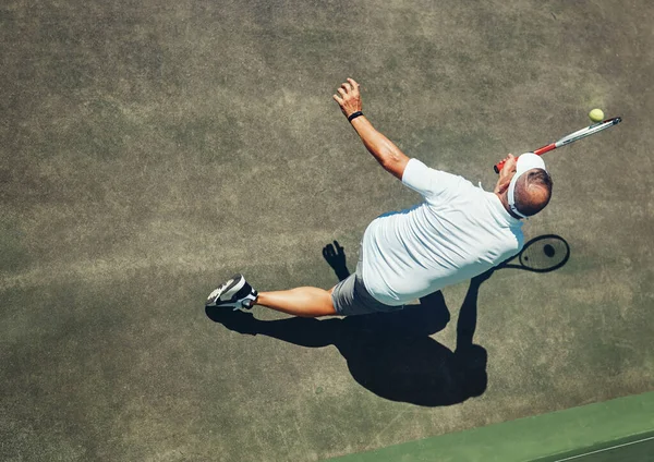 Це було близько. Високий кут стрільби зосередженого чоловіка середнього віку, який грає в теніс на вулиці на тенісному корті вдень . — стокове фото