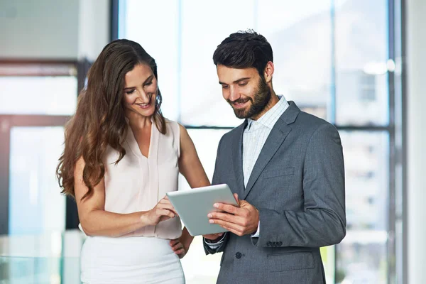 Zakelijke discussies digitaal gedaan. Foto van een jonge zakenman en zakenvrouw die samen een digitale tablet gebruiken in een kantoor. — Stockfoto