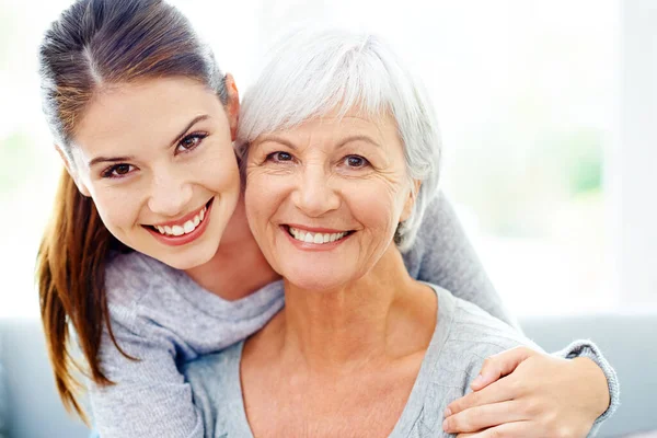 Mutter und Tochter ähneln sich. Eine attraktive junge Frau lächelt neben ihrer älteren Mutter. — Stockfoto