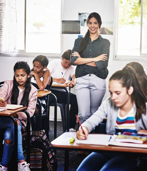 Ihr könnt mir die Ausbildung eurer Kinder anvertrauen. Porträt einer attraktiven jungen Lehrerin, die mit verschränkten Armen in einem Klassenzimmer steht. — Stockfoto