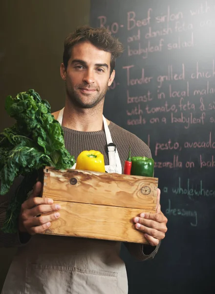 Er liebt sein Gemüse. Aufnahme eines jungen Mannes, der in seiner Küche eine Kiste mit frischem Gemüse hält. — Stockfoto