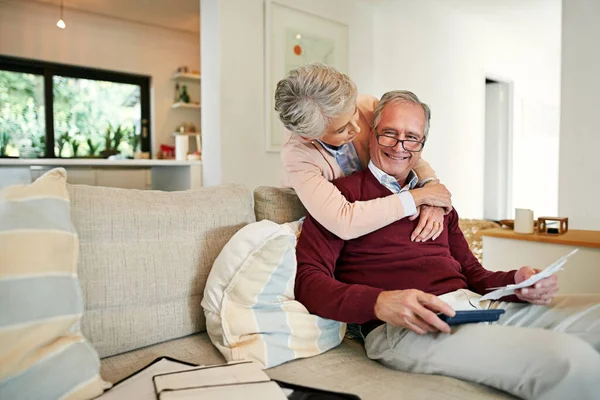 Youll be well rewarded for spending under the budget. Shot of a senior woman embracing her husband while he works out their monthly budget.