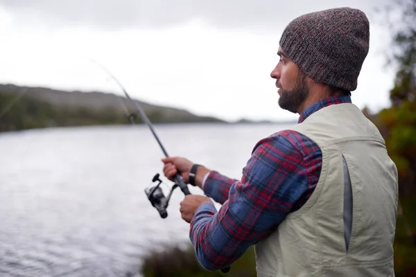 Esperando a que el pez muerda. Tiro de un hombre guapo pescando en un lago natural. —  Fotos de Stock