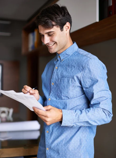 Flying through his paperwork. Shot of a handsome young businessmen holding some paperwork in his hands. Stock Image