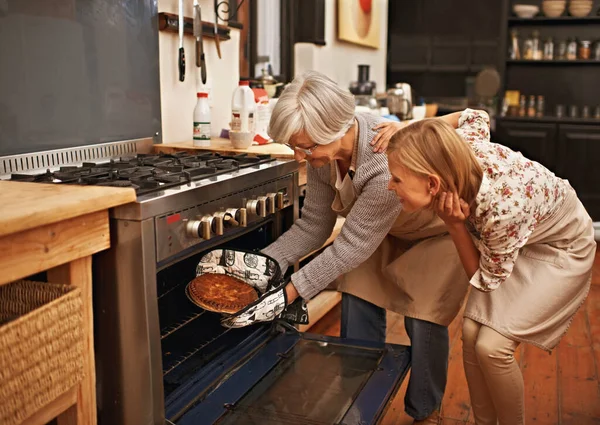 Getting baked. Shot of young woman learning baking tips from her grandmother. — Stock Photo, Image