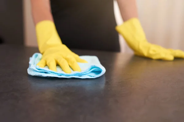 Tertemiz ve mikropsuz. Evdeki bir bez parçasıyla mutfak masasını silerken lastik eldiven takan birinin kırpılmış görüntüsü.. — Stok fotoğraf