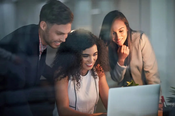 Blij om hun hoofden bij elkaar te zetten. Foto van drie collega 's die samenwerken op een laptop in het kantoor. — Stockfoto