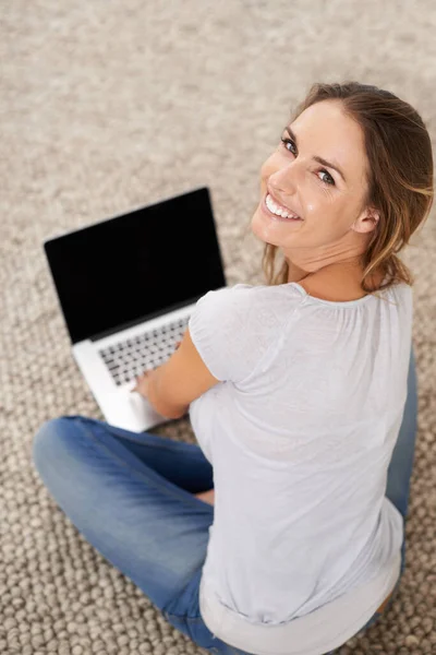 Il mio portatile e 'come il mio armadio di amici. Una giovane donna seduta sul tappeto del suo salotto con il suo portatile. — Foto Stock
