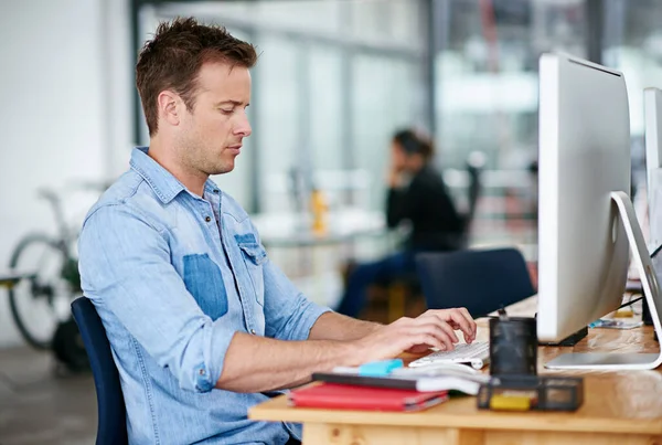 He wont stop until he gets the job done. Shot of a handsome young man working at his desk in an office. — ストック写真