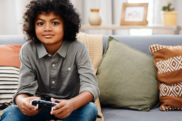 Mindig készen állok egy kihívásra. Vágott lövés egy imádnivaló kisfiú ül a kanapén, és játszik videojátékok otthon. — Stock Fotó