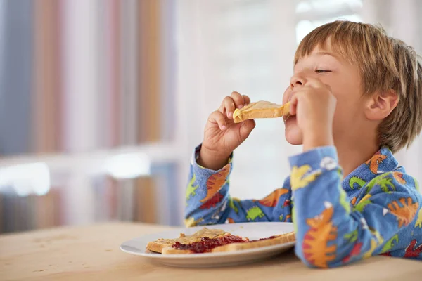 Sabroso brindis. Un niño lindo desayunando. — Foto de Stock