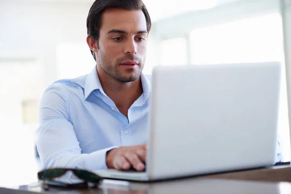 Hard werken om zijn deadline te halen. Een foto van een knappe zakenman die aan zijn laptop aan zijn bureau werkt.. — Stockfoto