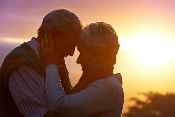 Szeress gyengéden, szeress igazán... kivágott kép egy idős párról, akik egy romantikus pillanaton osztoznak naplementekor.. — Stock Fotó