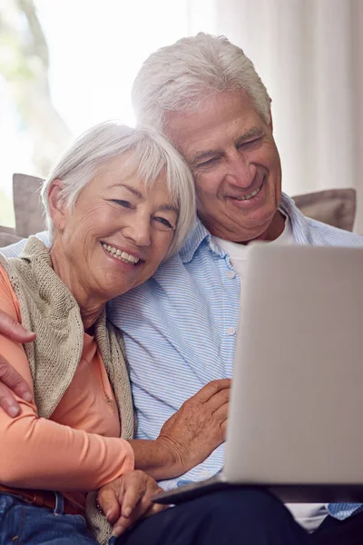 Ver comedias románticas en línea. Fotografía de una pareja de ancianos usando un portátil en casa. — Foto de Stock