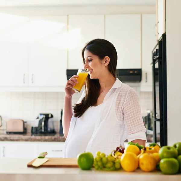 Gezond leven staat gelijk aan een gezonde baby. Schot van jonge zwangere vrouw die thuis een glas sinaasappelsap drinkt. — Stockfoto
